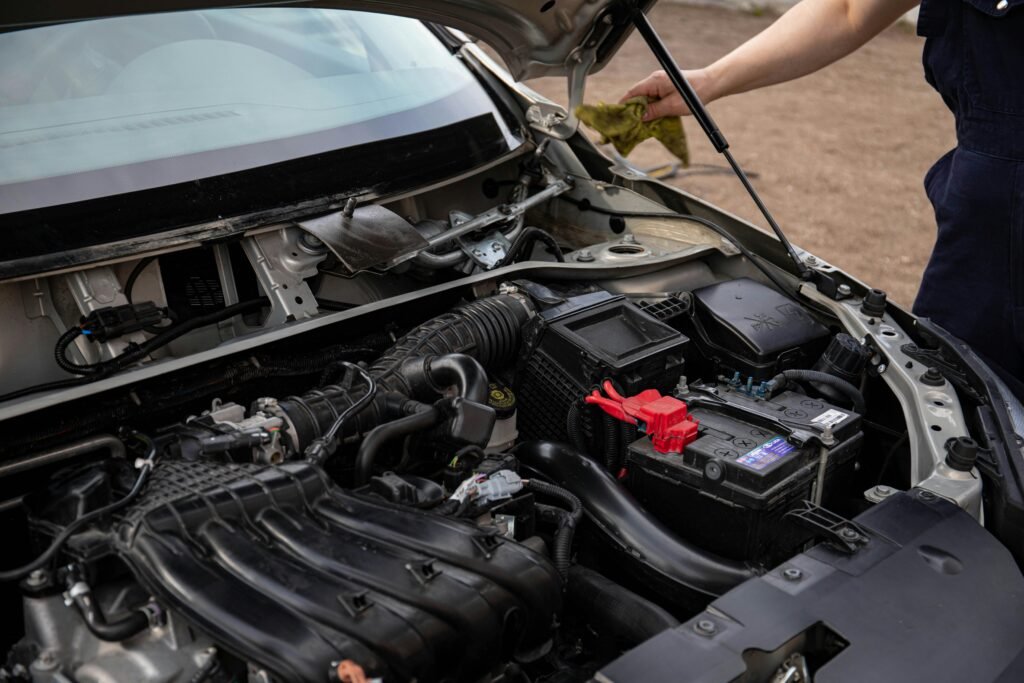 Car battery replacement service Dubai — mechanic inspecting car battery under open hood